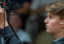 Bundesfreiwilligendienst im Sport: Dein Jahr in der Tischtennis Bundesliga beim ASC Cameraman operating a professional video camera on a tripod, facing left and focusing on the shot, wearing a dark shirt.
