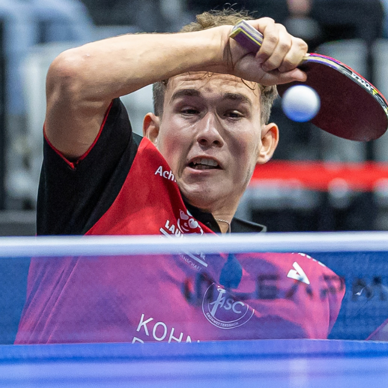 ASC 2 gegen Versbach: Damian Floro im rotschwarzen ASC Trikot nach einem Vorhandschlag, den Schläger über dem Kopf, der Ball fliegt knapp an seinem Gesicht vorbei.